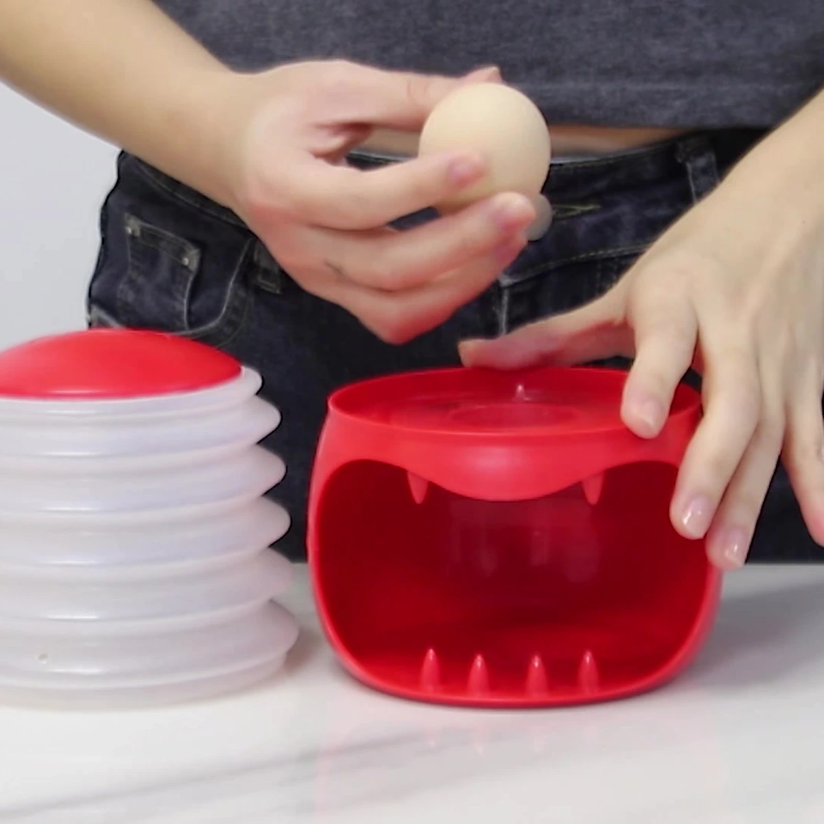 Red egg holder and removable white accordion air dome separated before a cooled hard-boiled egg is placed