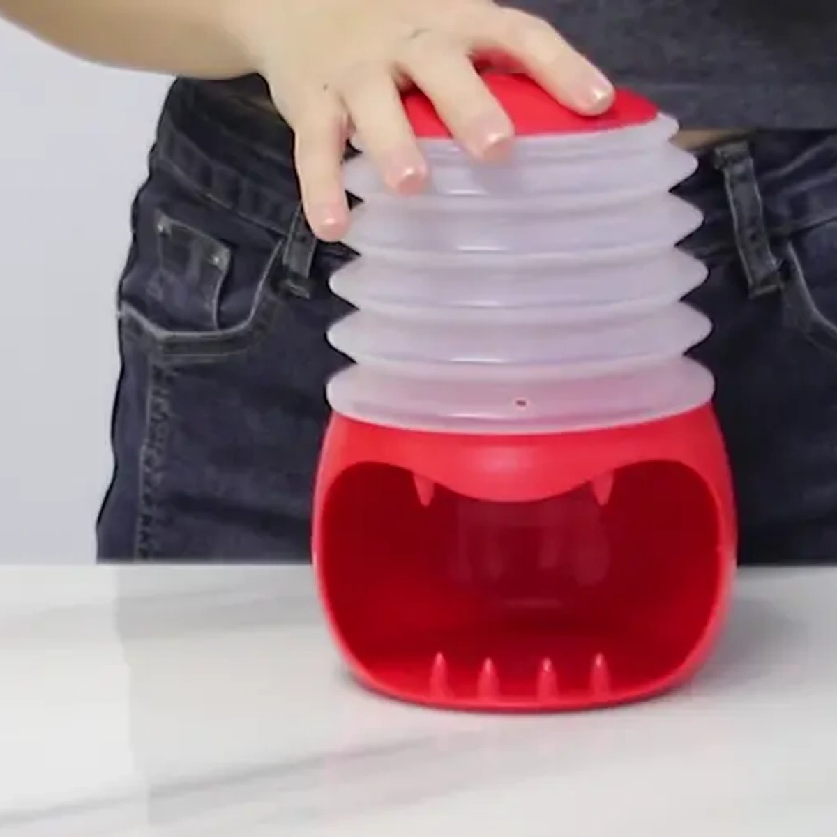Boiled egg peeler being pressed over a prepared cooled egg on a kitchen counter